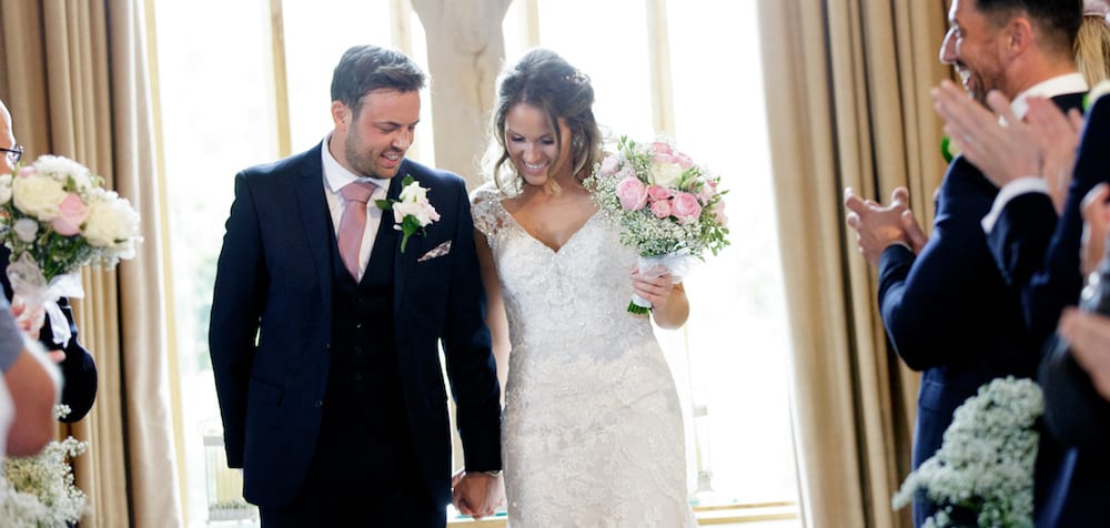 newlyweds just married walking back up the aisle holding blush pink bridal bouquet