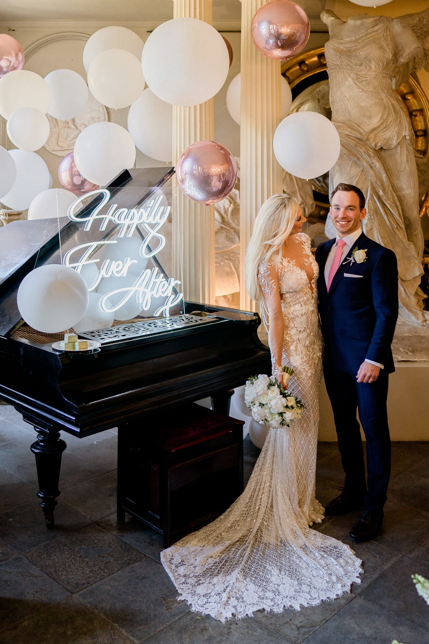 white balloons embellishing the black grand piano with neon sign