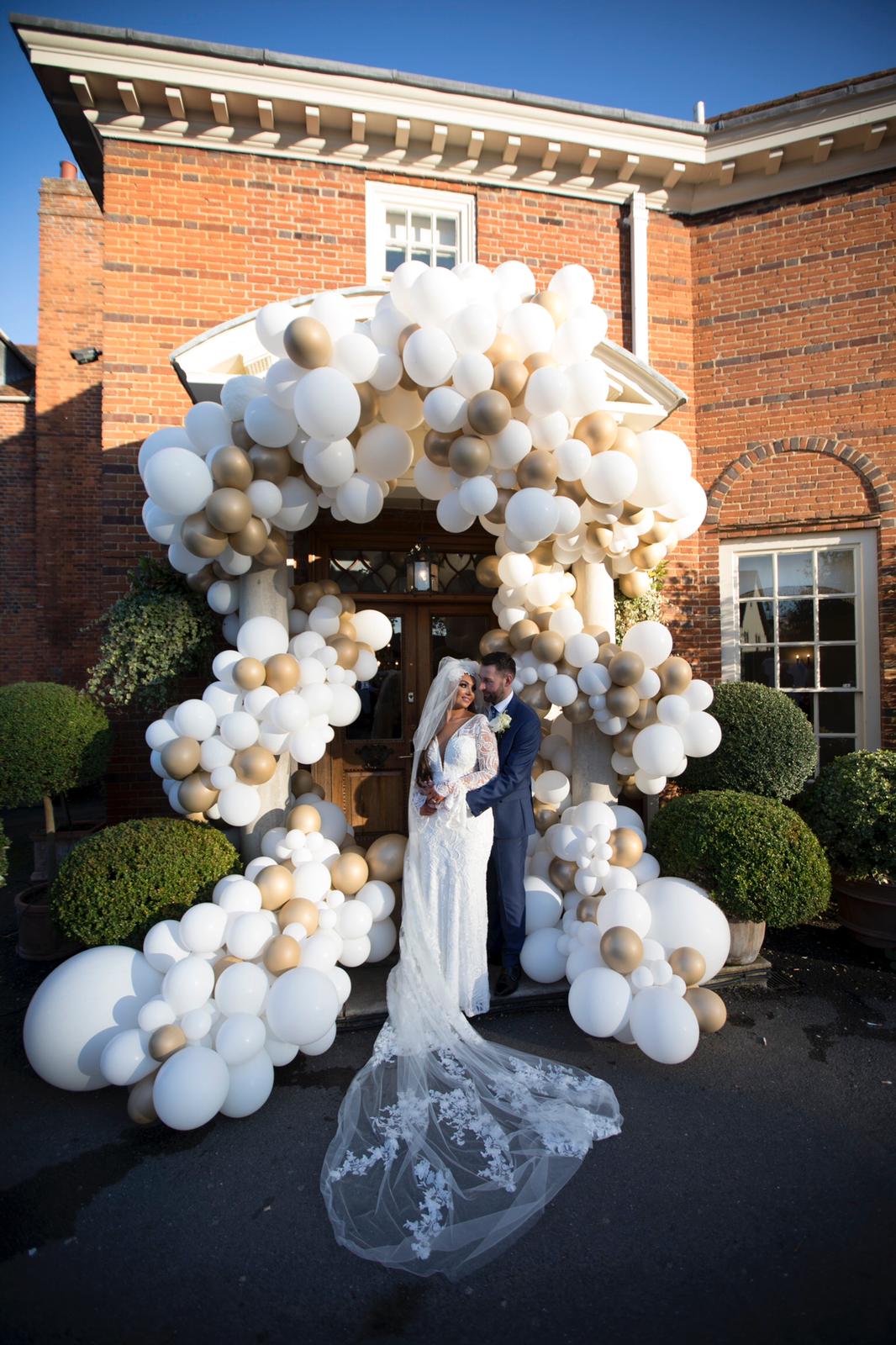 white and gold balloon archway to wedding venue