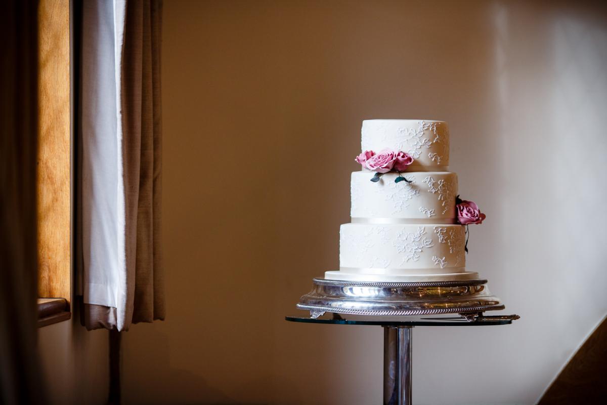 three tiered white wedding cake with floral detailing