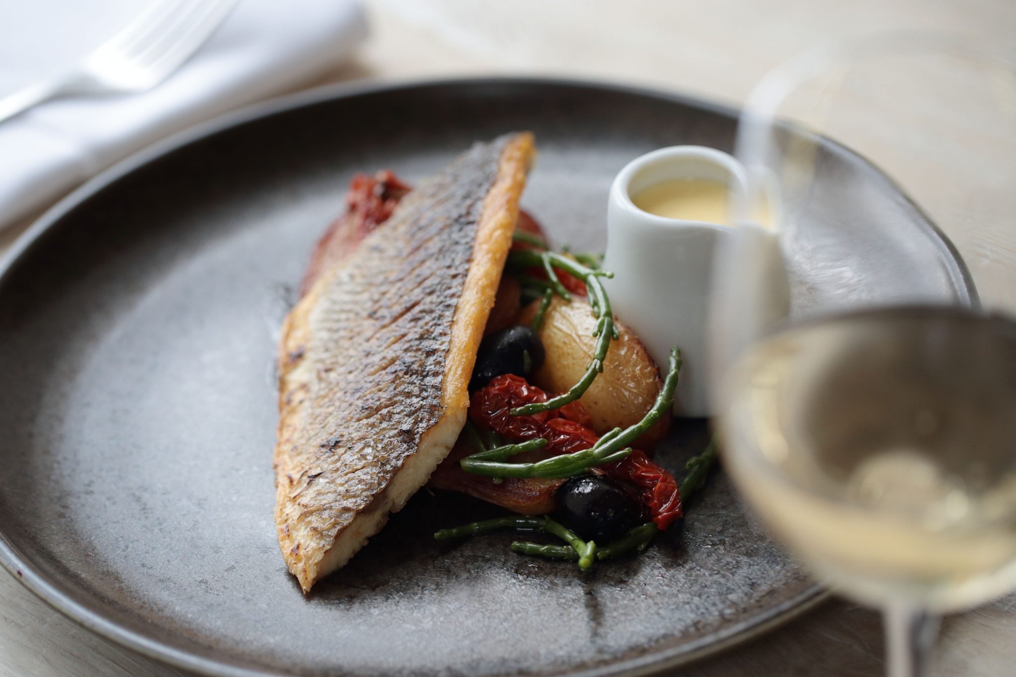 Fillet of seabass, Italian new potatoes, baby tomato, olive, rocket and butter sauce